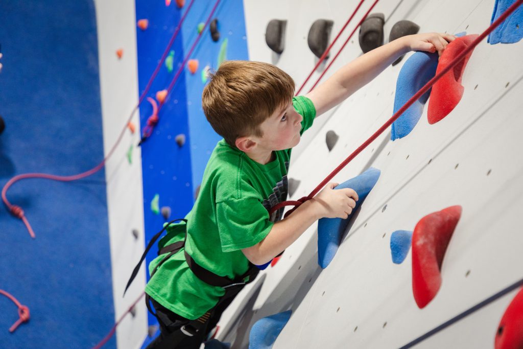 Young climber attached to ropes climbing at Hudson Boulders